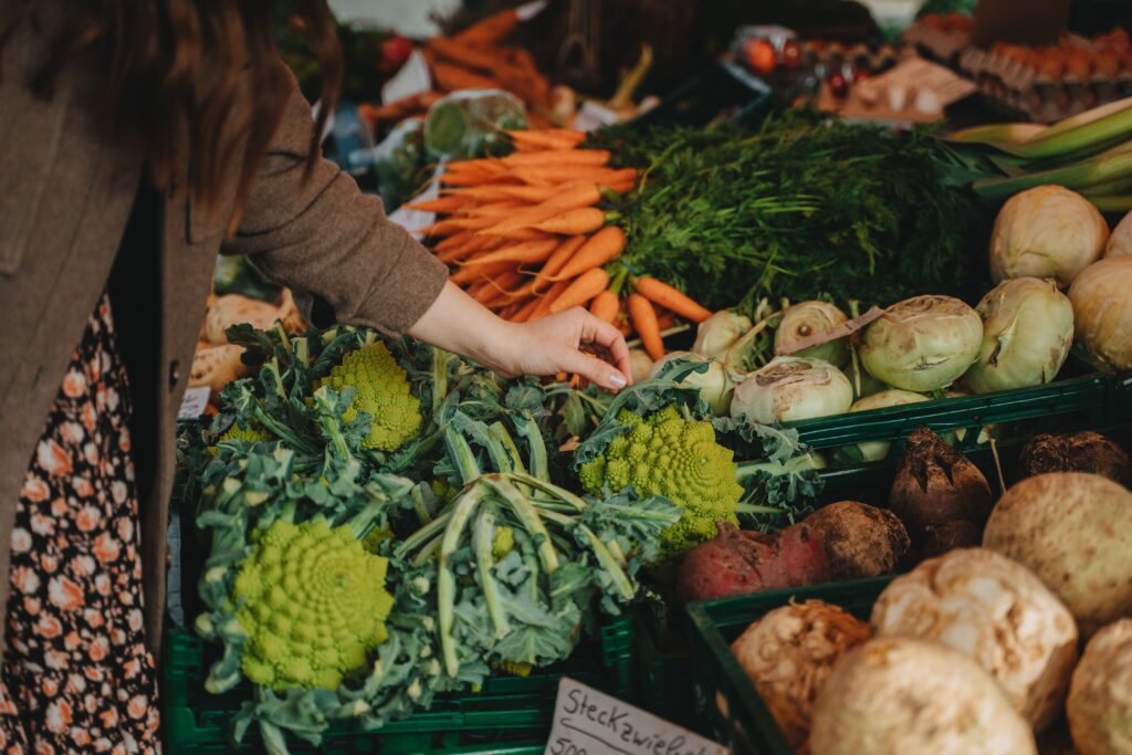 27. September: Flashmob am Herbstmarkt in Reigoldswil Woman selecting fresh vegetables at a vibrant local farmers market.